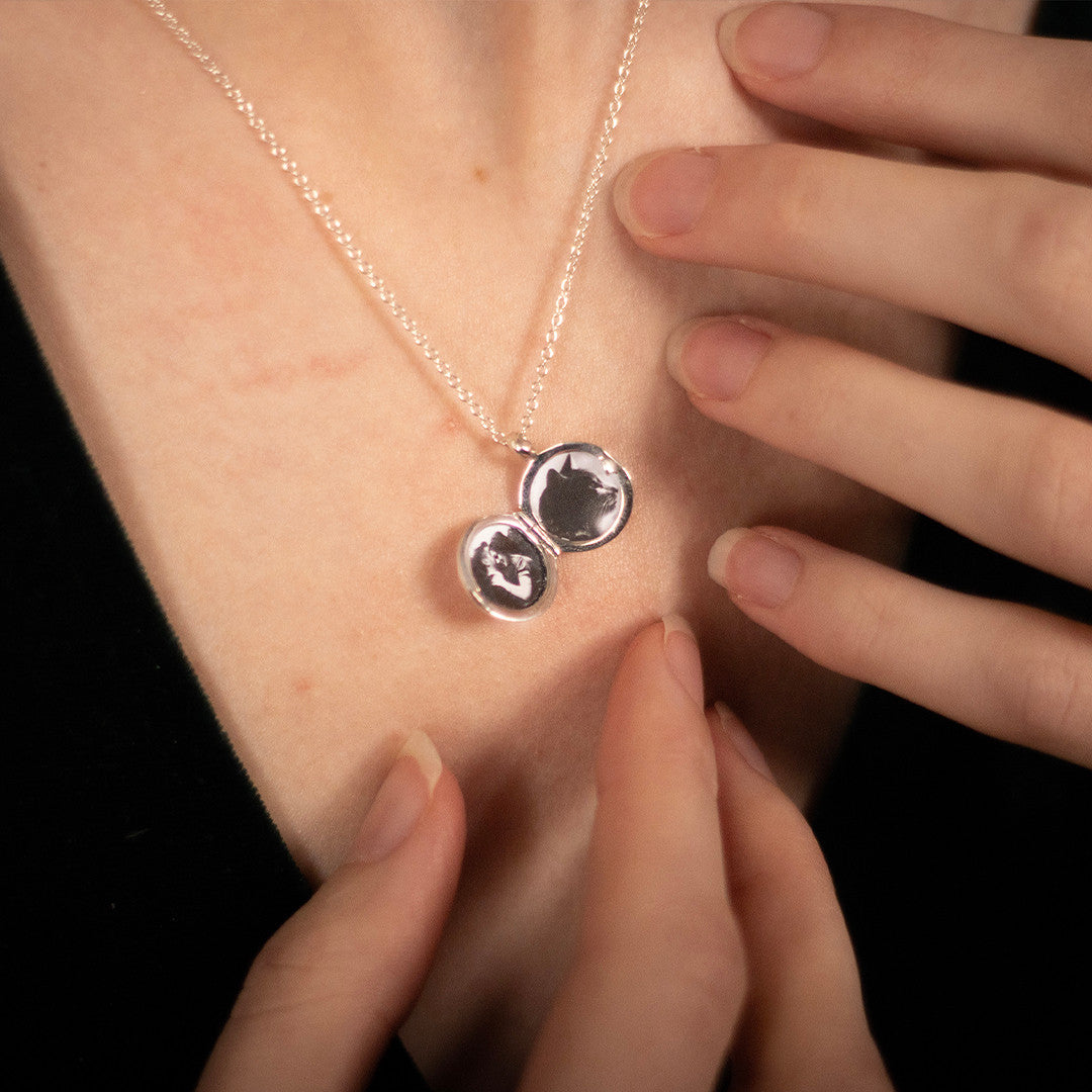 model wearing opened small round diamond locket in silver