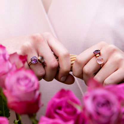 model wearing four cocktail rings in gold whilst holding basket of flowers