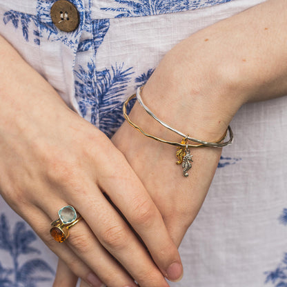 model wearing gold bangle with silver seahorse charm attached