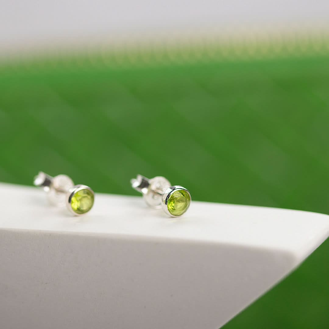 Peridot mini stud earrings in silver on a white surface