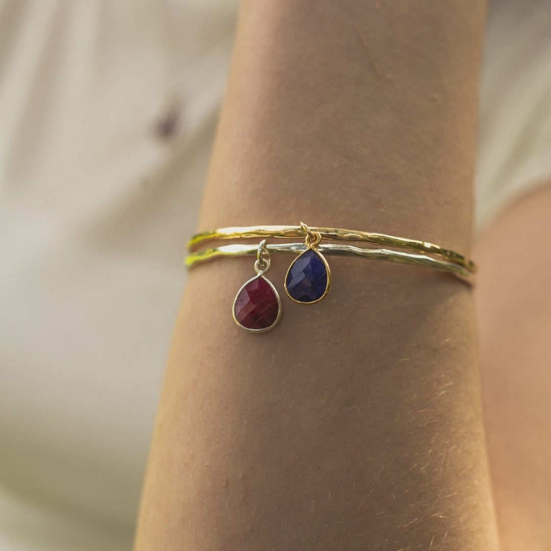 close up of model wearing two birthstone charm bangles in gold
