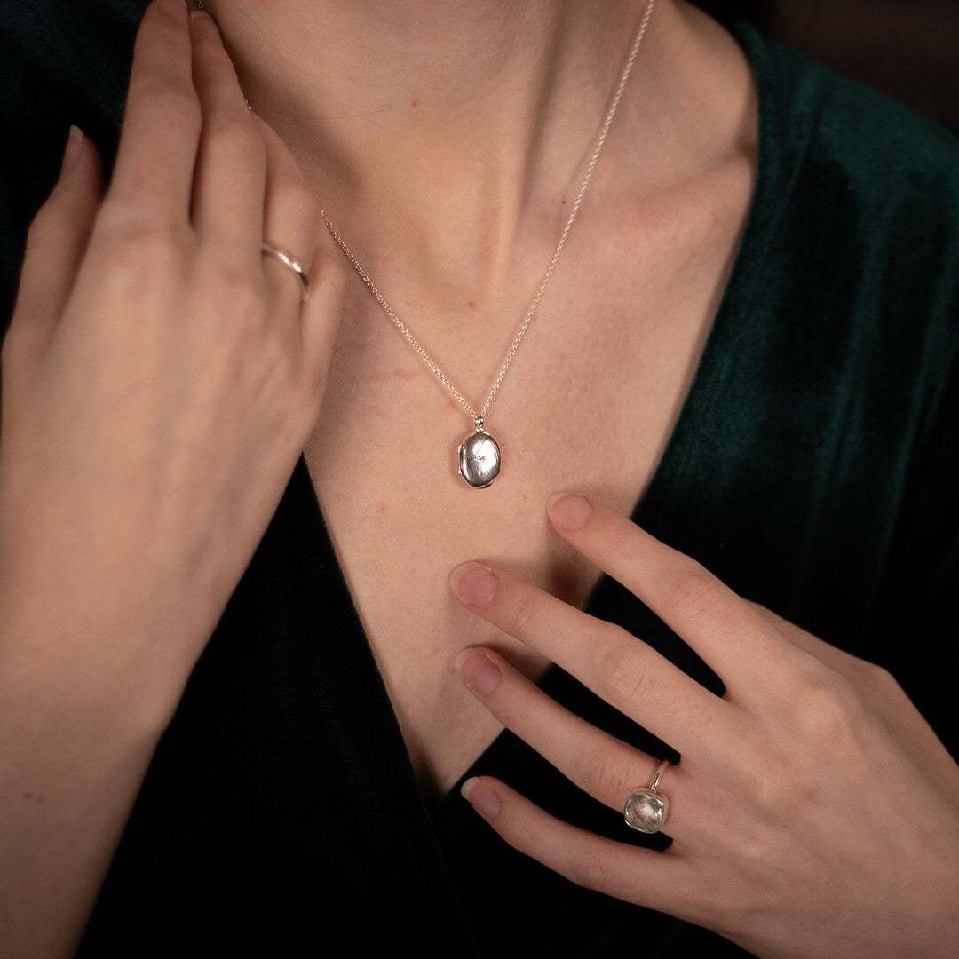 women modelling small oval diamond locket in silver