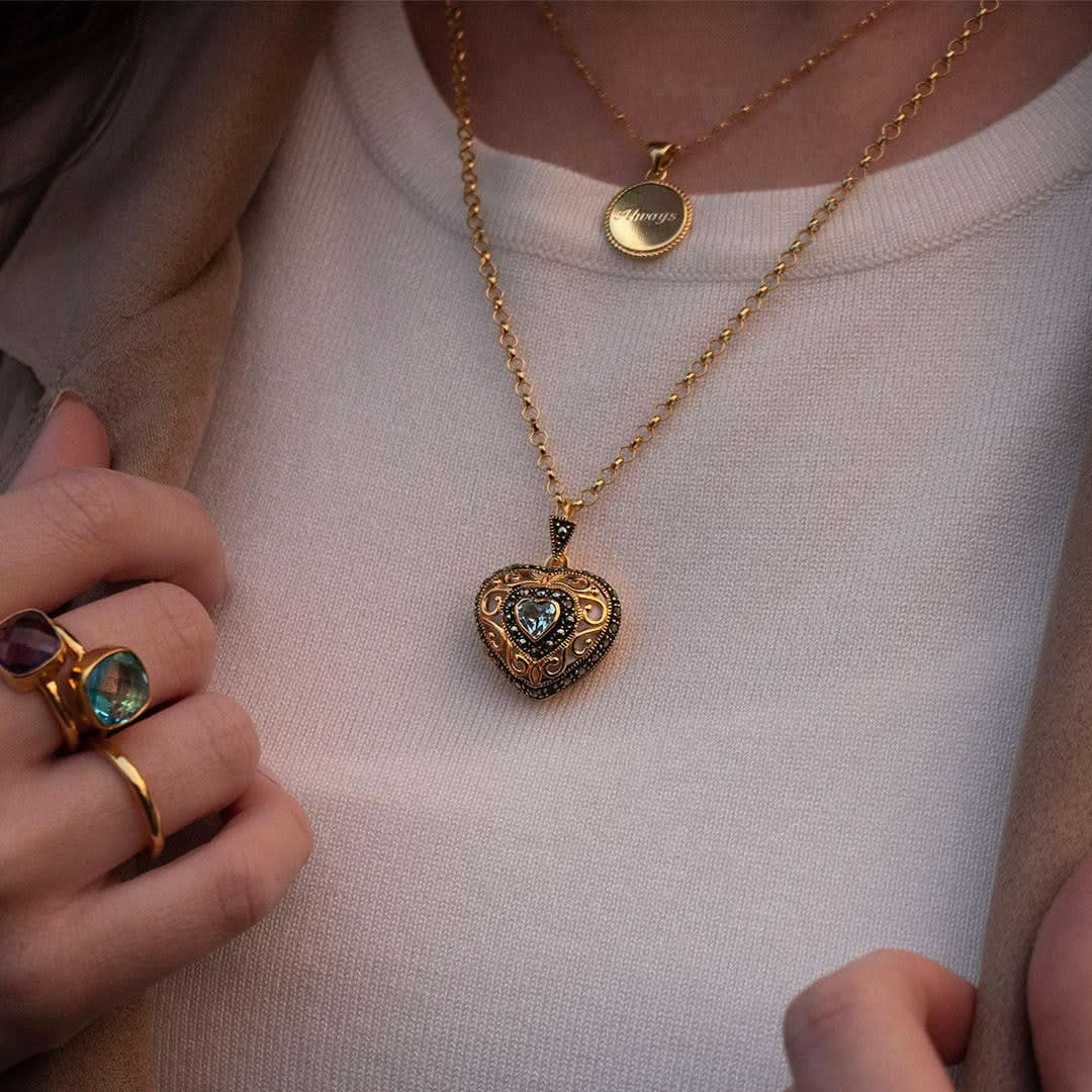 model in white top wearing gold vintage heart locket with topaz gemstone