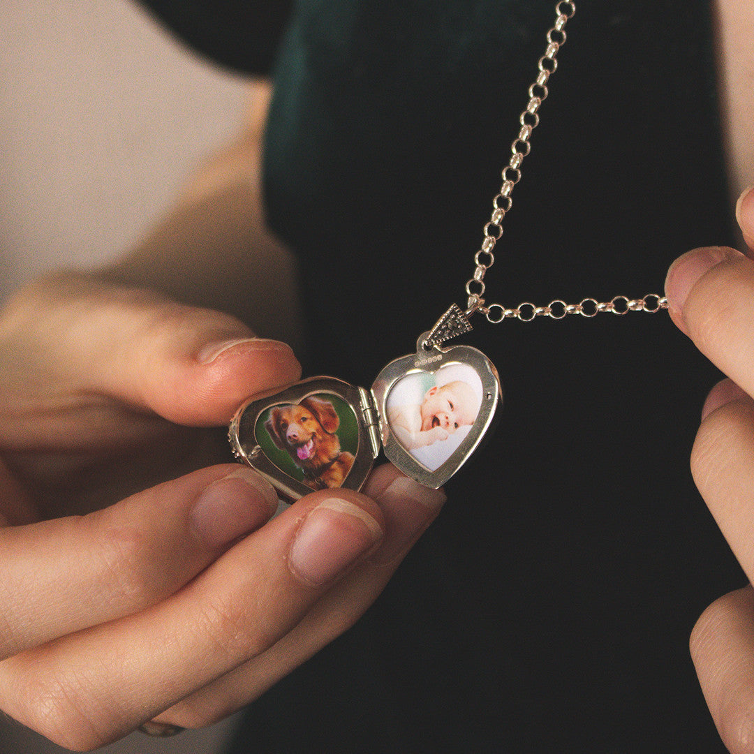 women holding emerald vintage heart locket in silver to reveal family photos