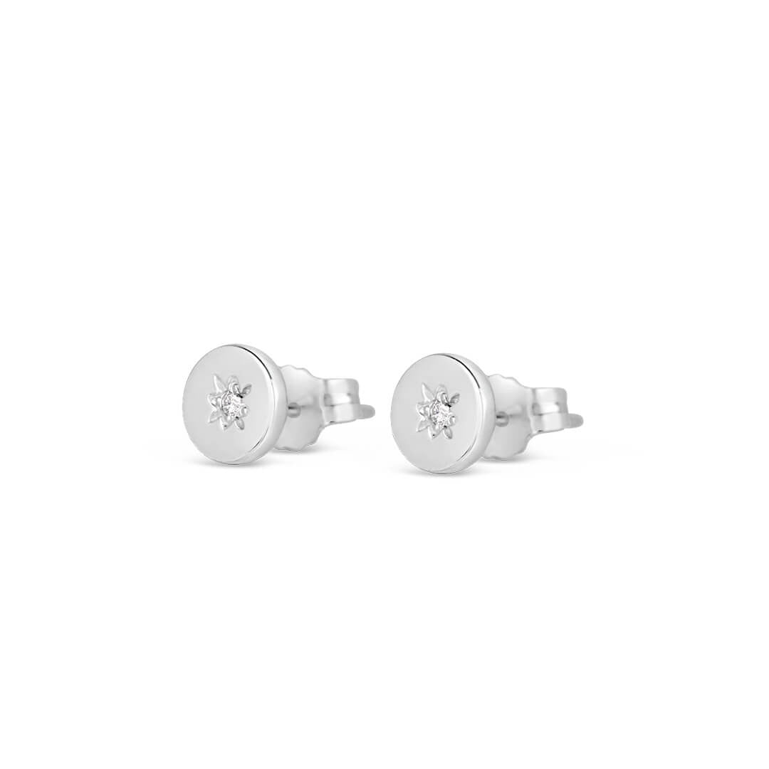 silver circular stud style earrings with a diamond decoration on a white background