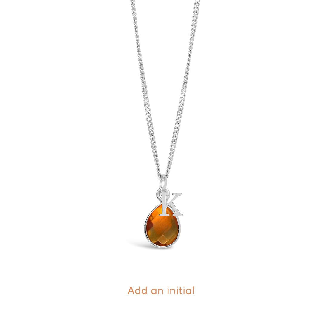 citrine charm necklace with initial charm on a white background