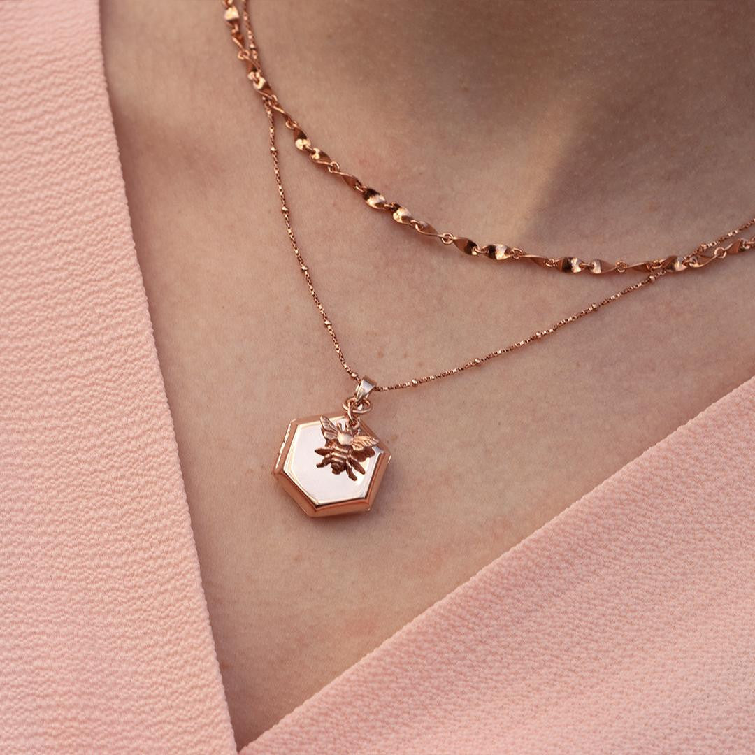 closeup of model wearing rose gold bee locket with charm