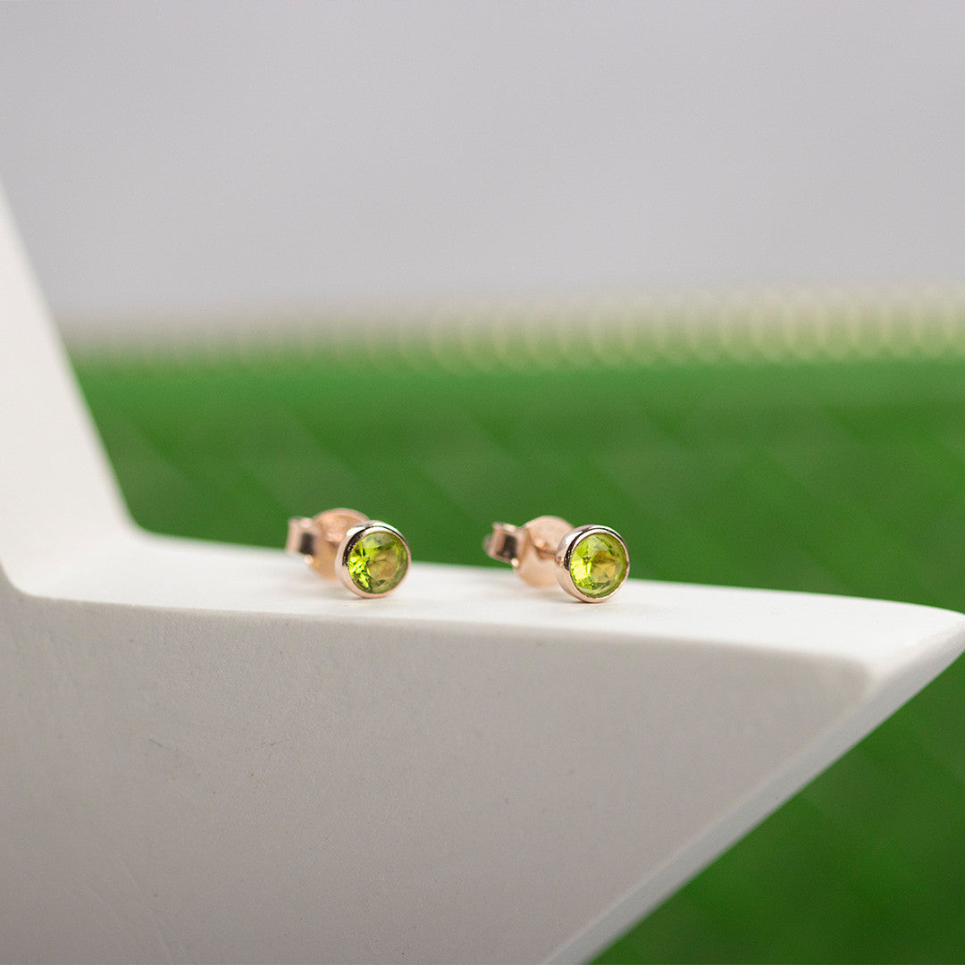 Peridot mini stud earrings in rose gold on white surface
