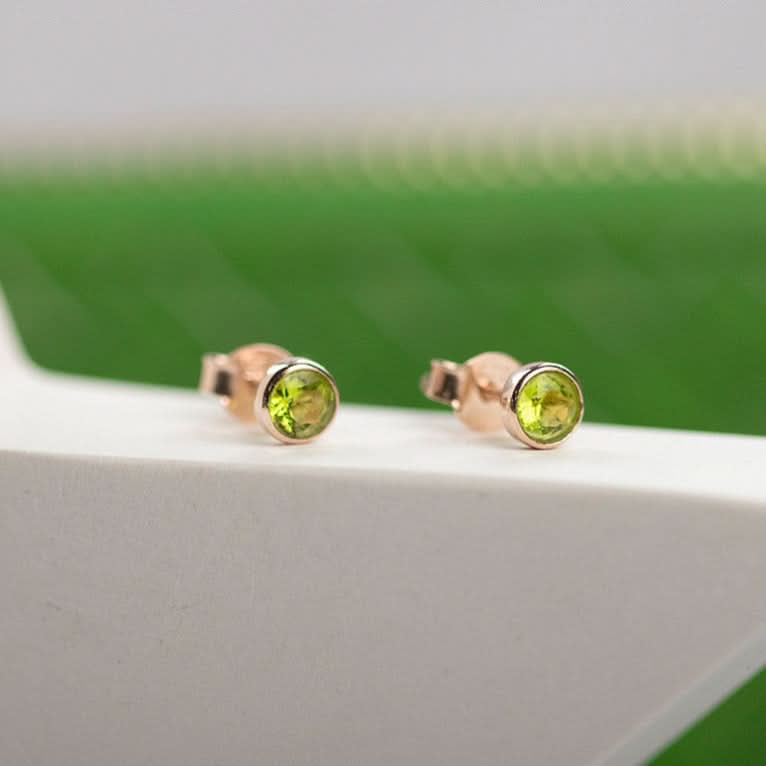 Peridot mini stud earrings in rose gold on white surface