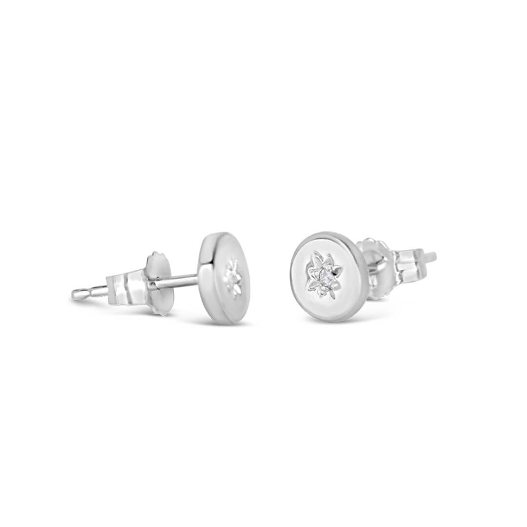 side on perspective of a pair of silver stud style earrings with a diamond decoration