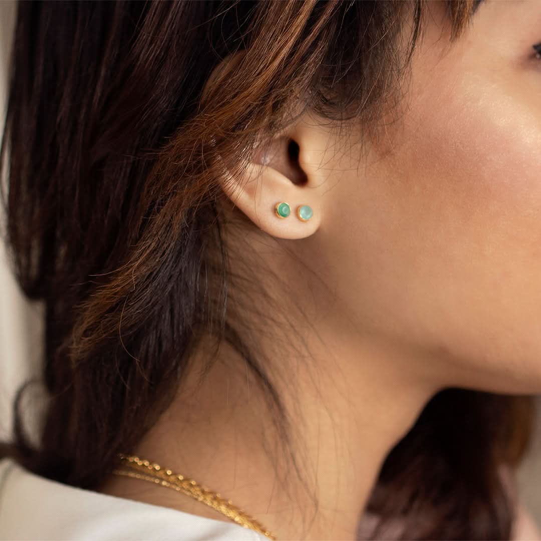 model wearing rose gold mini stud earrings with emerald gemstone