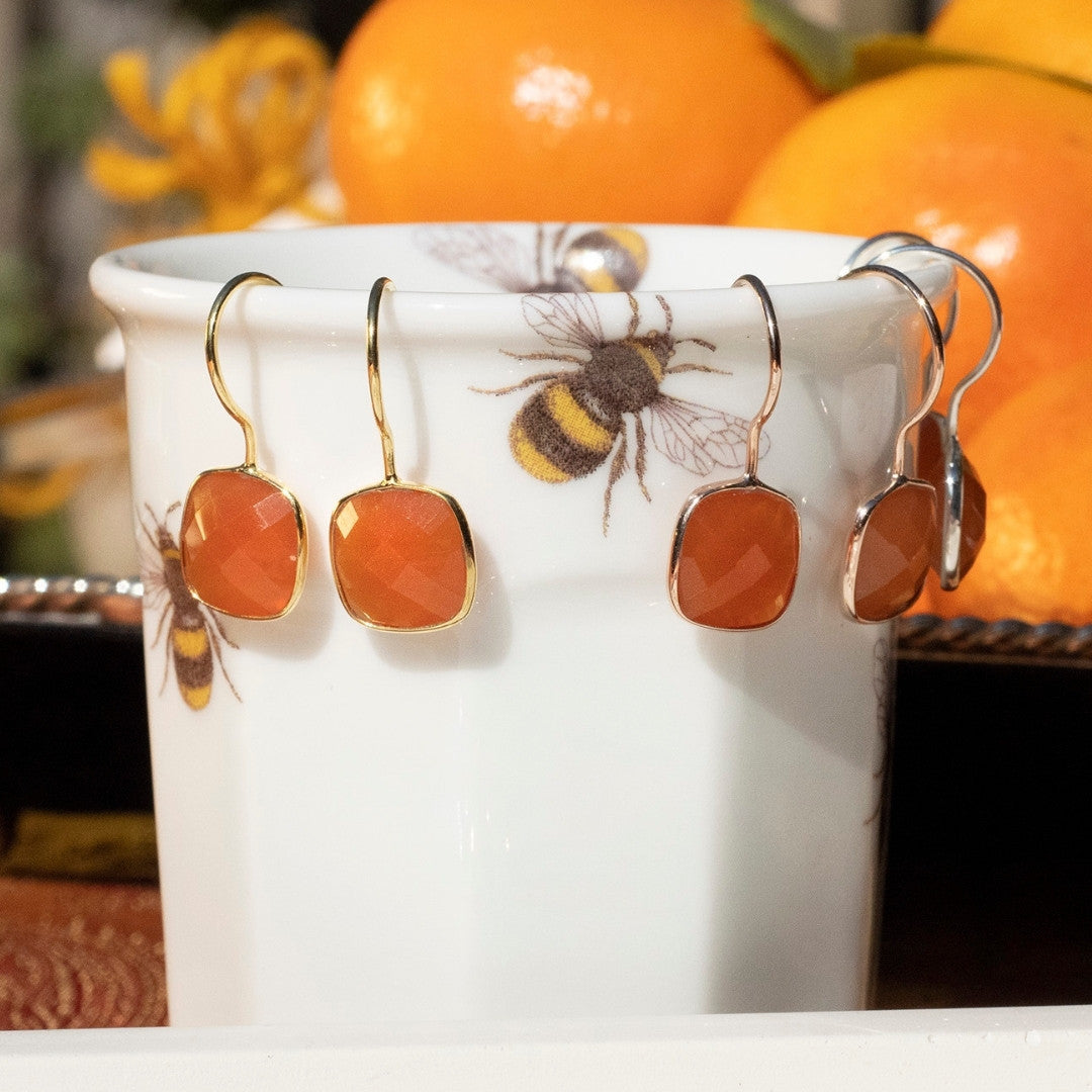 close up of carnelian earrings in silver with oranges in the background