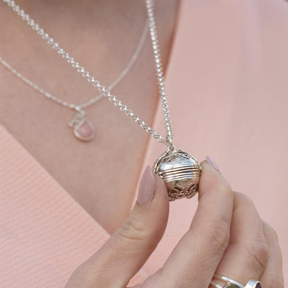 model in pink top holding white gold memory keeper locket