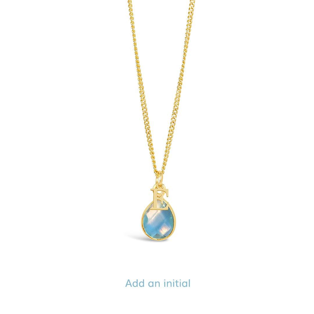 blue topaz charm necklace with initial charm in gold on a white background