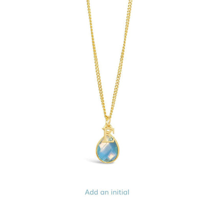blue topaz charm necklace with initial charm in gold on a white background