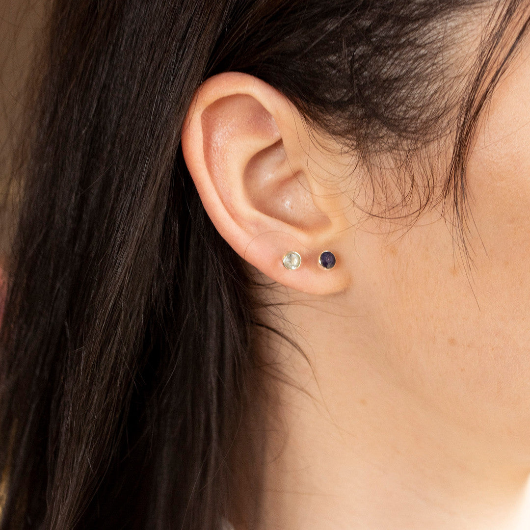Model image wearing blue topaz mini stud earrings in gold