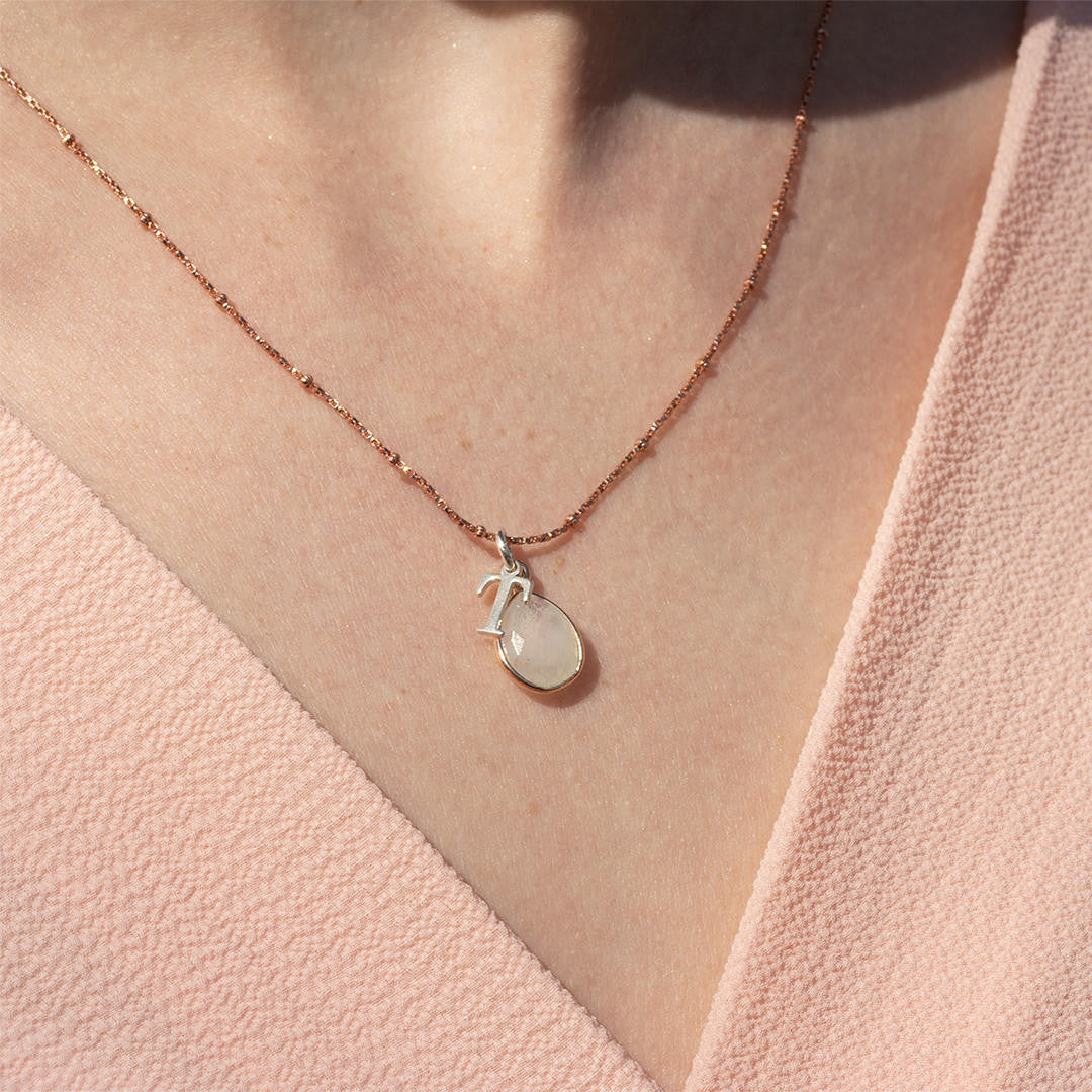 close up of model wearing moonstone charm necklace with silver initial charm