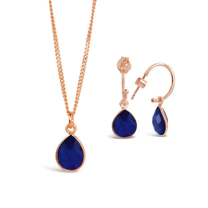 sapphire charm necklace and drop hoop earrings on a white background