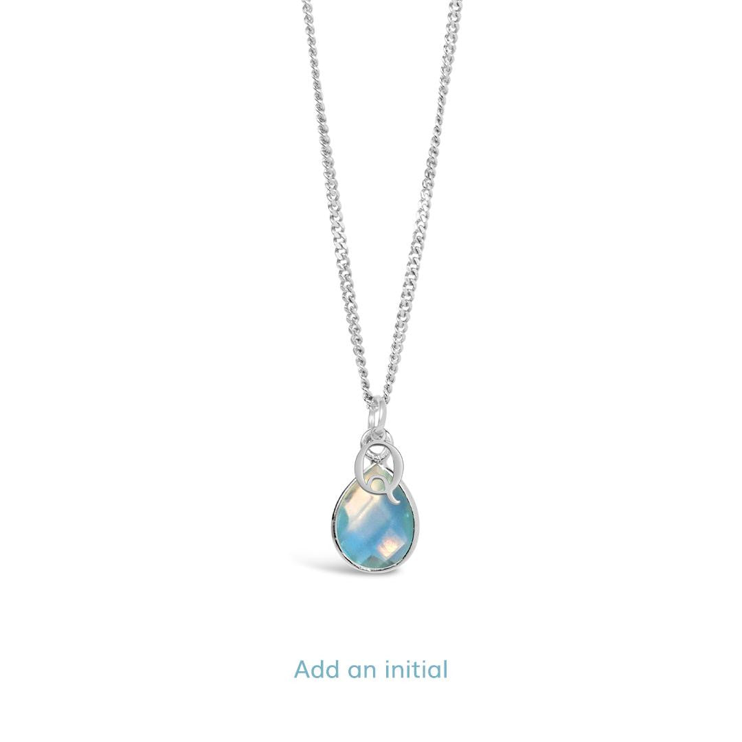 blue topaz charm necklace in silver with initial charm on a white background