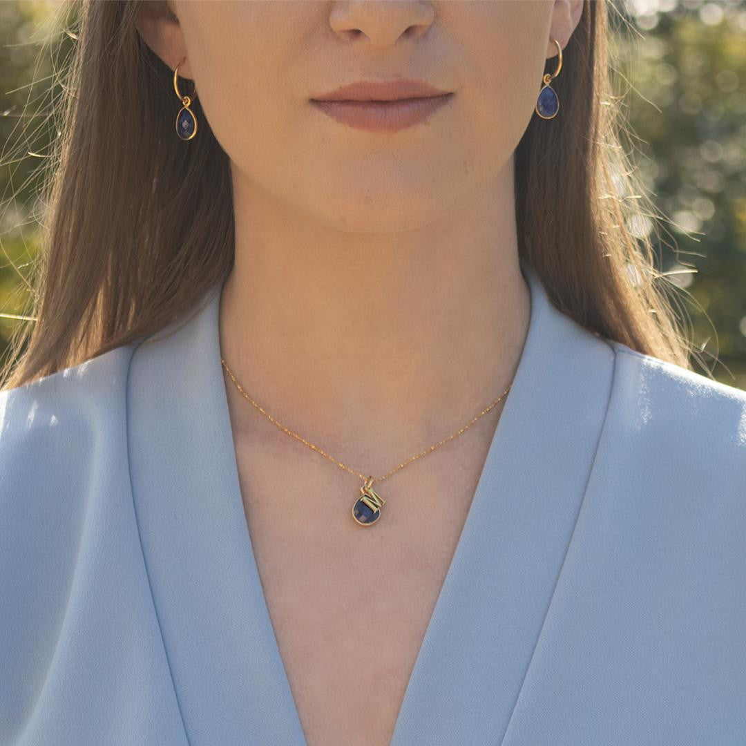 model wearing sapphire charm necklace in gold with initial charm