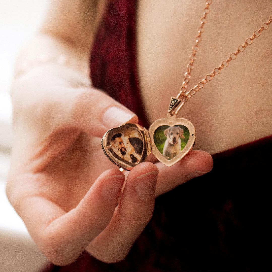 Model holding heart shaped rose gold locket and showing the photos inside