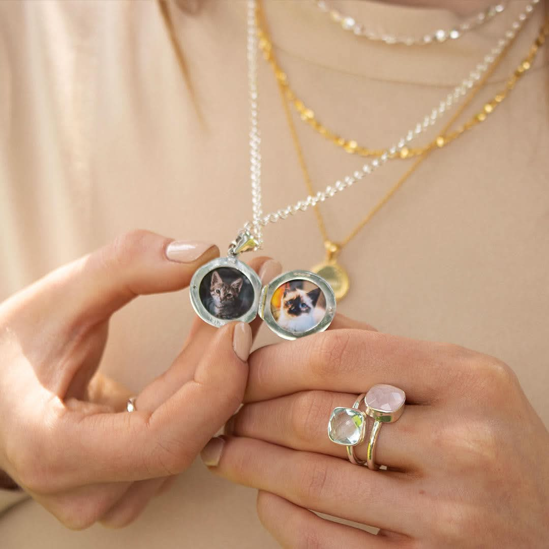 closeup of model wearing opened round locket in white gold with photos inside