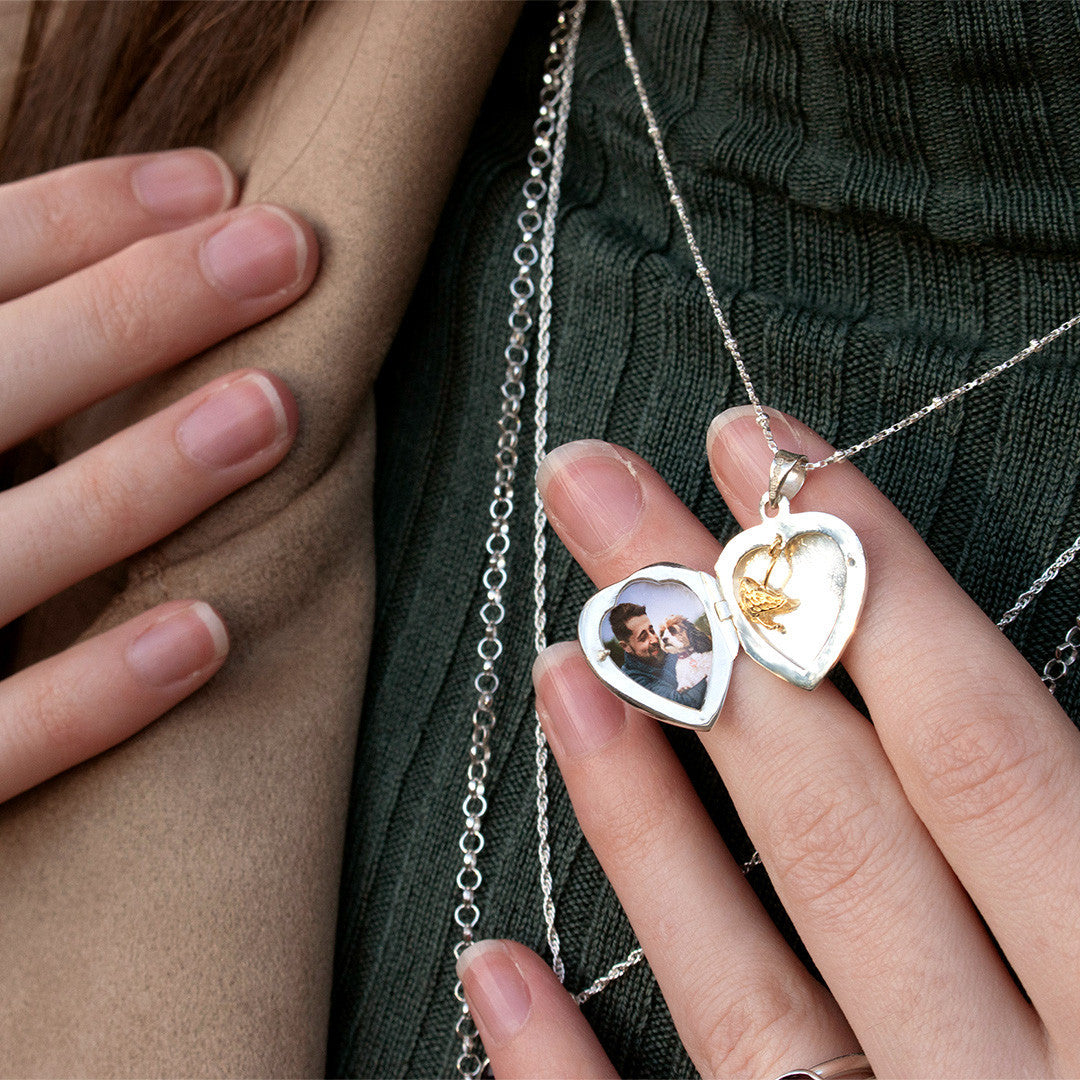 model wearing opened secret silver heart locket with gold bird and photo inside