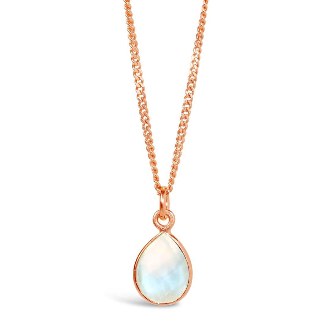 A natural moonstone charm necklace in a rose gold setting, hanging from a rose gold curb chain, photographed on a white background.