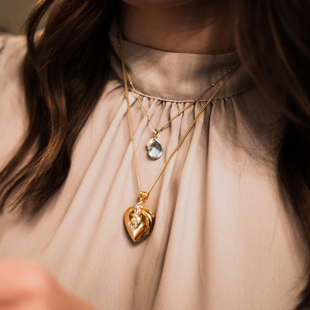 model wearing blue topaz charm necklace in gold