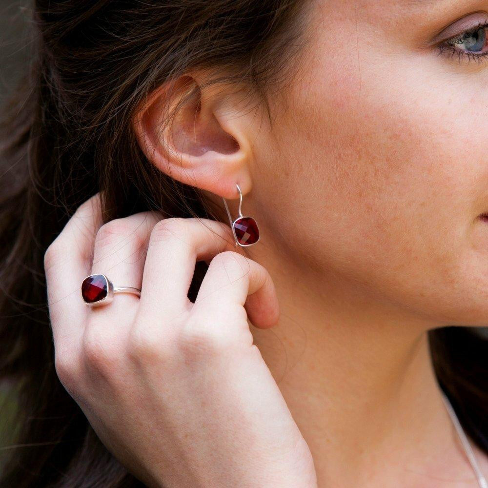 close up of model wearing garnet cocktail ring with matching earrings 