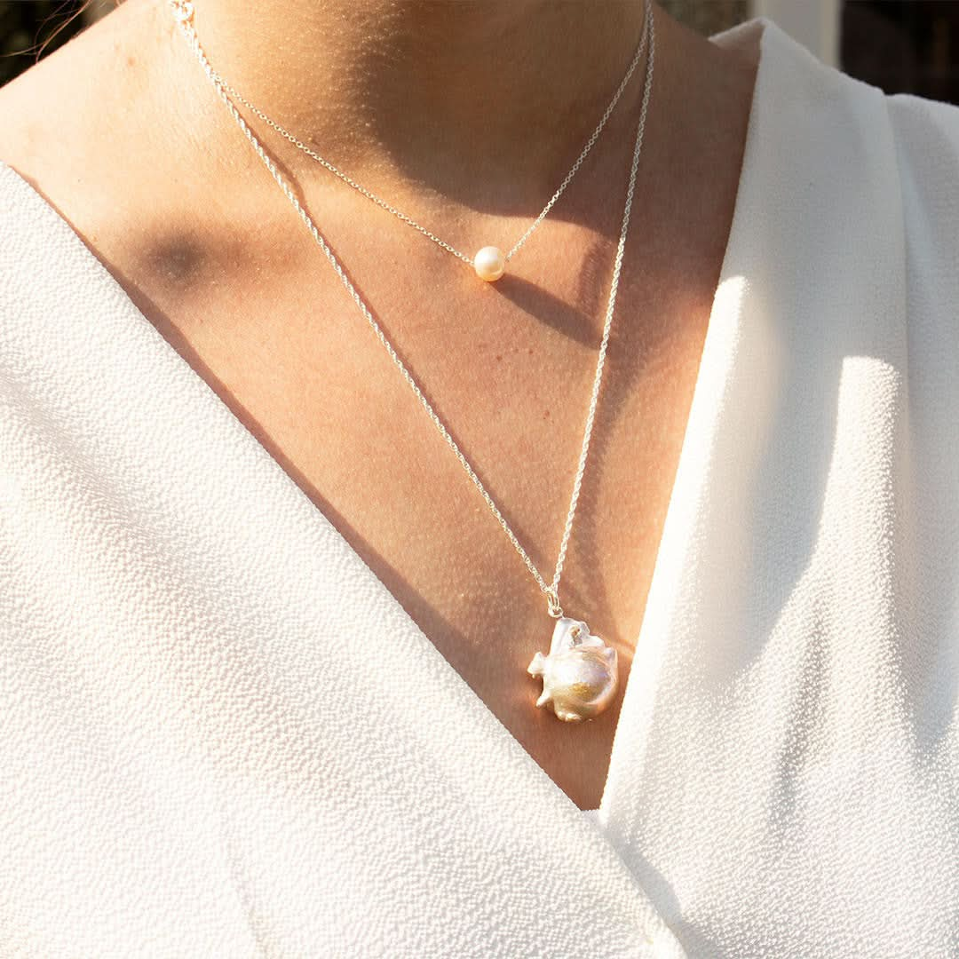 close up of model wearing pearl chain necklace in ivory silver