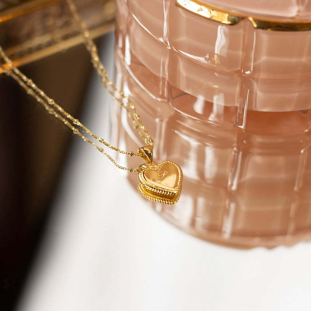 engravable heart necklace in gold sitting next to jewellery dish 