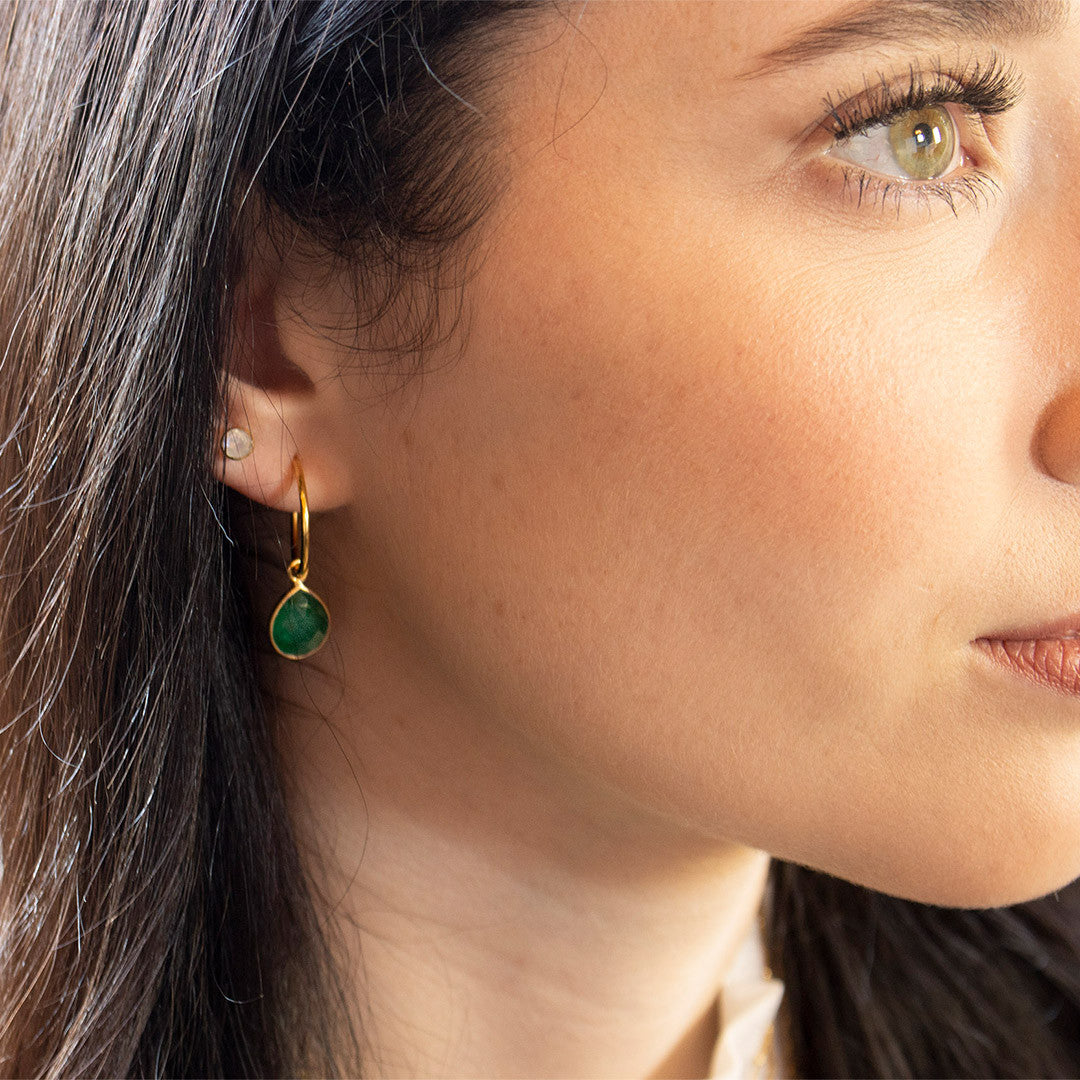 closeup of model wearing emerald drop hoop earrings 
