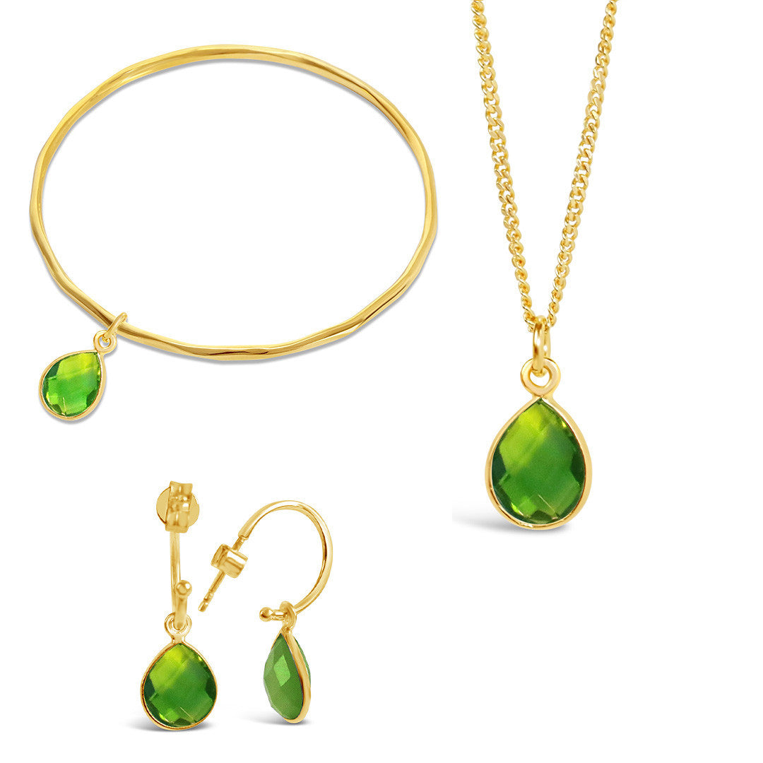 peridot charm bangle drop hoop earrings and necklace on a white background