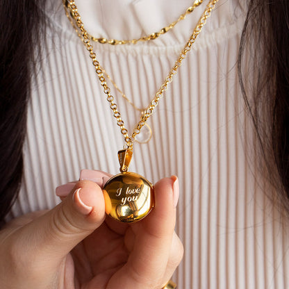 close up of model wearing round locket necklace in gold with engraved message 