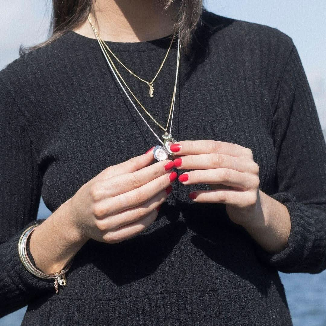 model wearing opened seahorse locket in silver