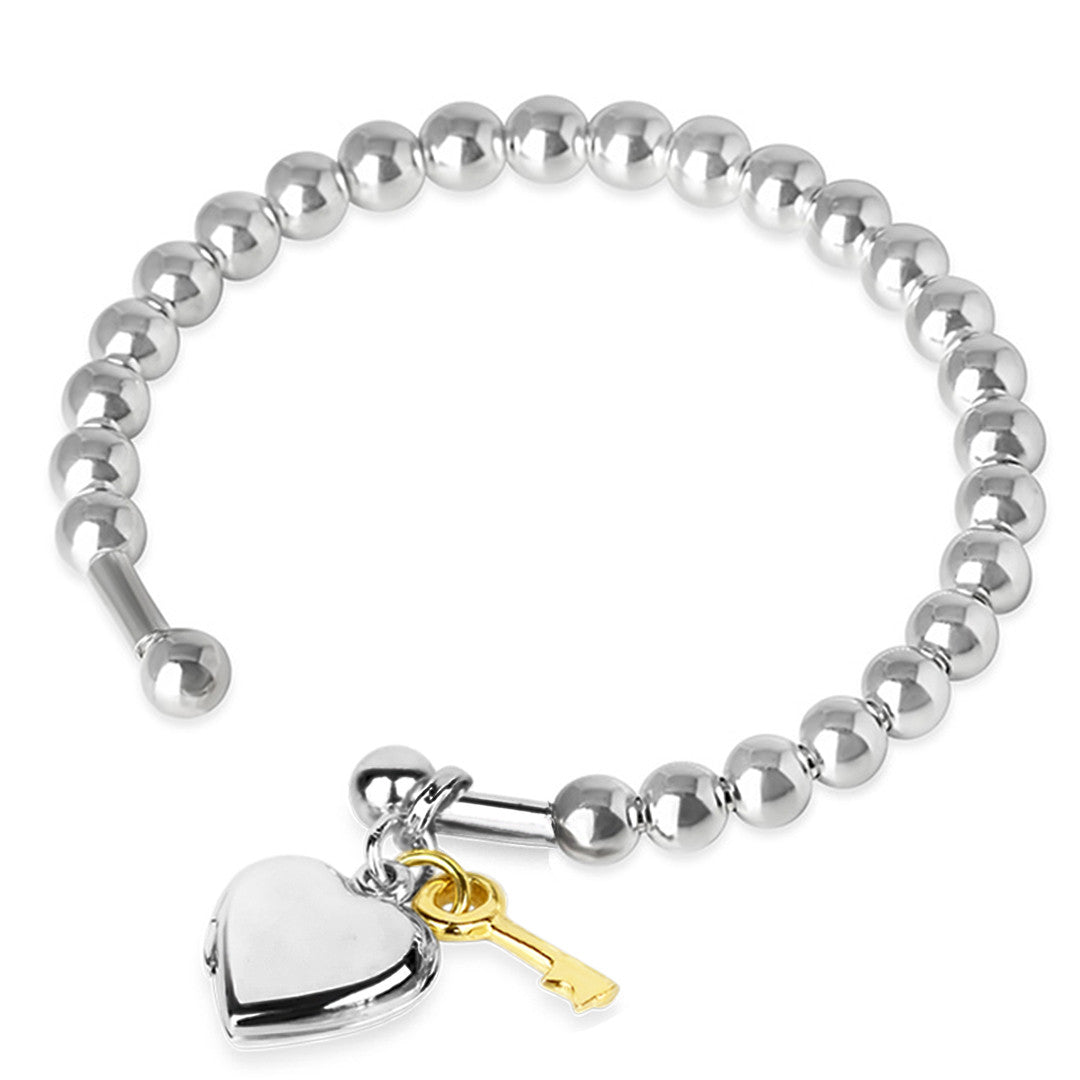 heart locket bangle in silver with gold key charm on a white background
