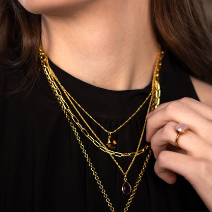 model wearing paperclip chain necklace in gold along with other gold jewellery