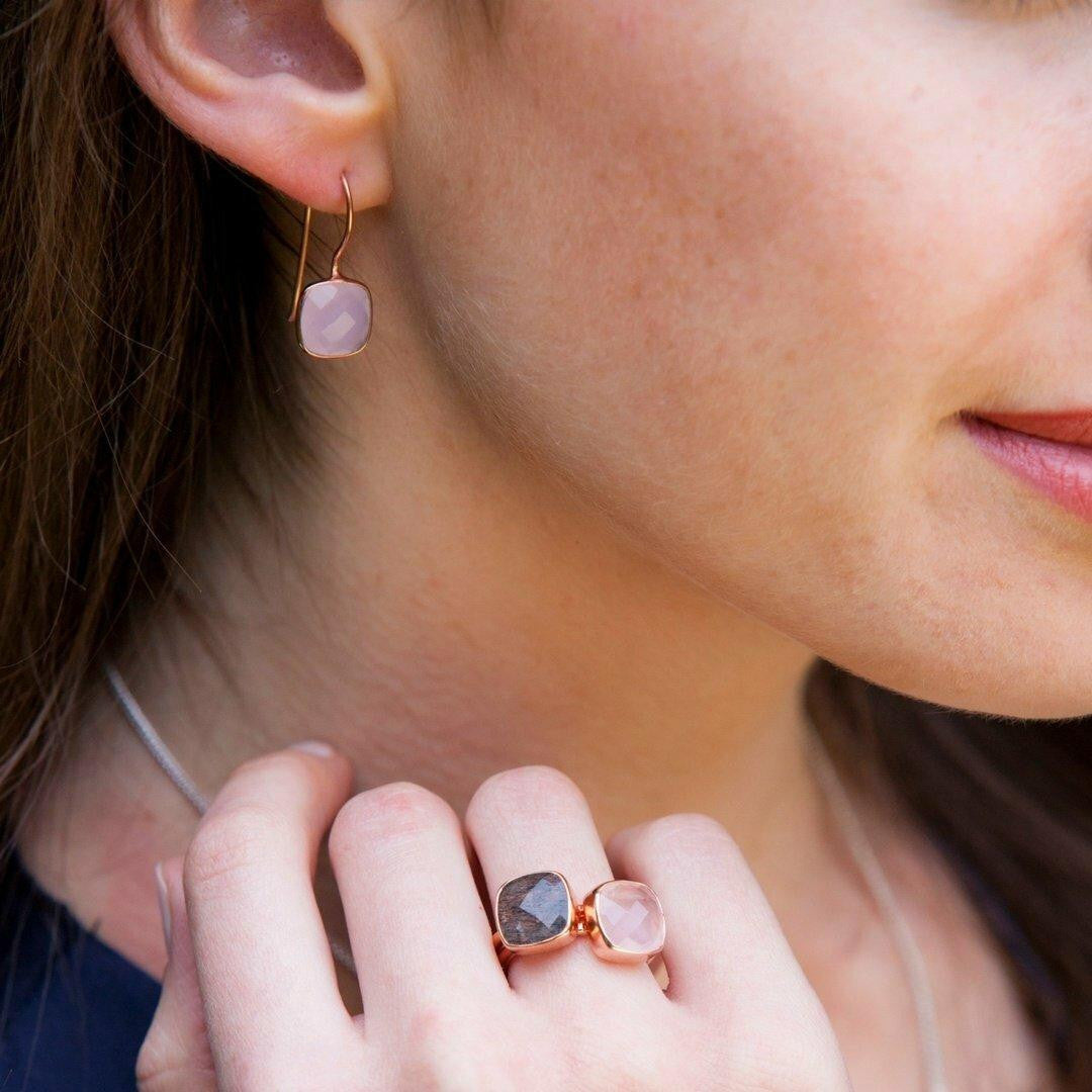 close up of model wearing rose quartz earrings and matching cocktail ring in rose gold