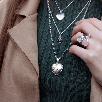 close up of model wearing white gold four photo heart locket with charm attached