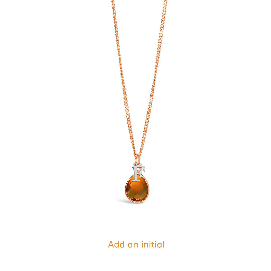 citrine charm necklace in rose gold with silver initial charm on a white background 
