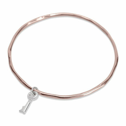 rose gold bangle with silver key charm attached on a white background
