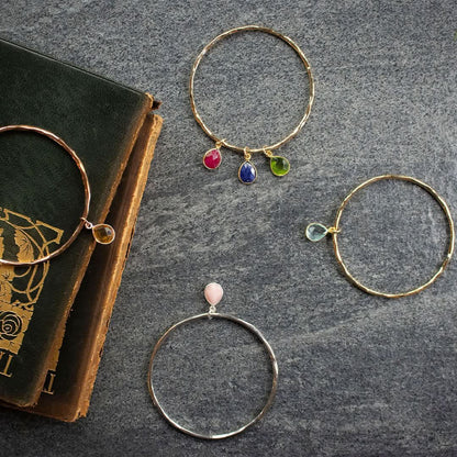 Lifestyle image of three birthstone bangles on grey slate