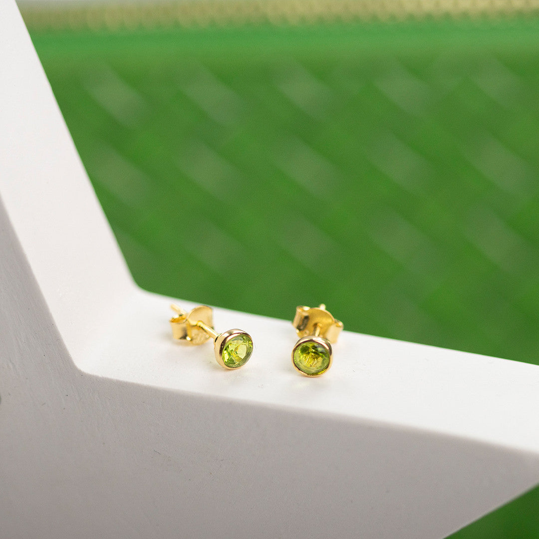 peridot stud earrings in gold on a white surface