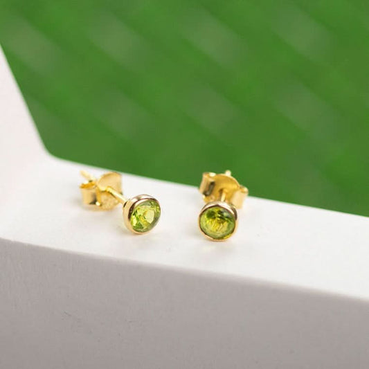 peridot stud earrings in gold on a white surface