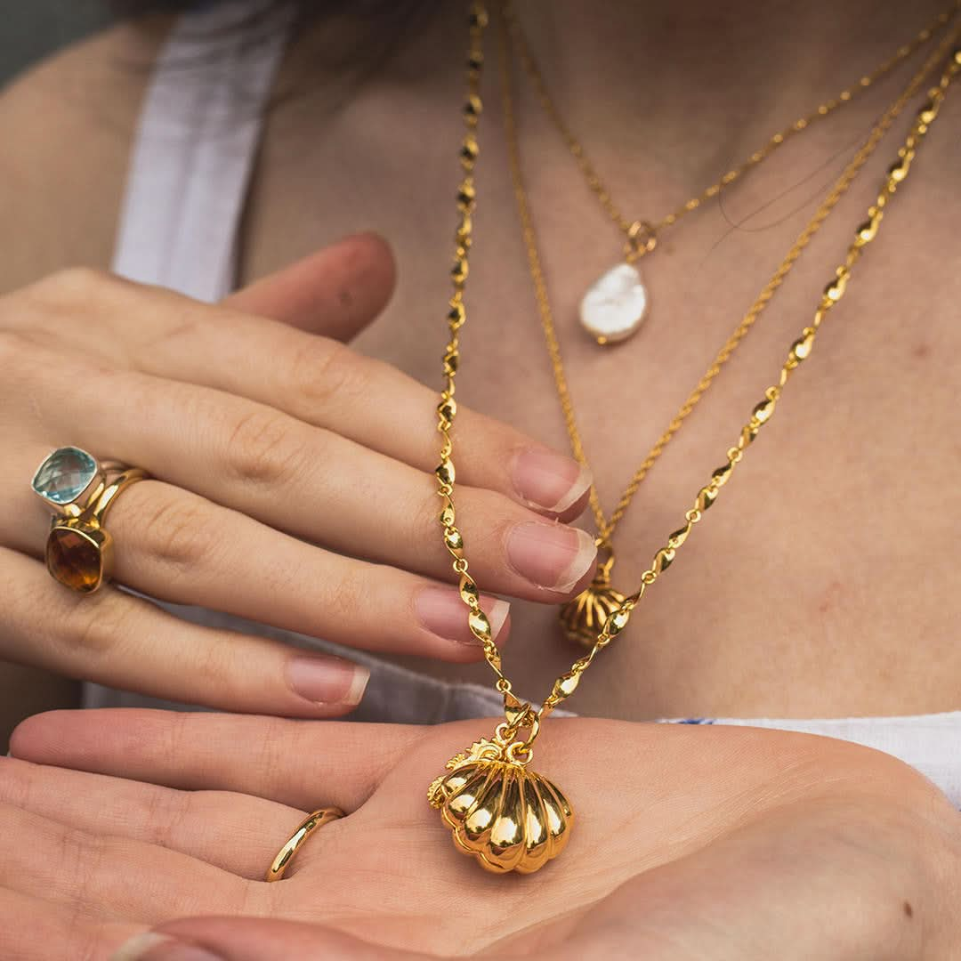 close up of model wearing gold seahorse locket on a twist chain