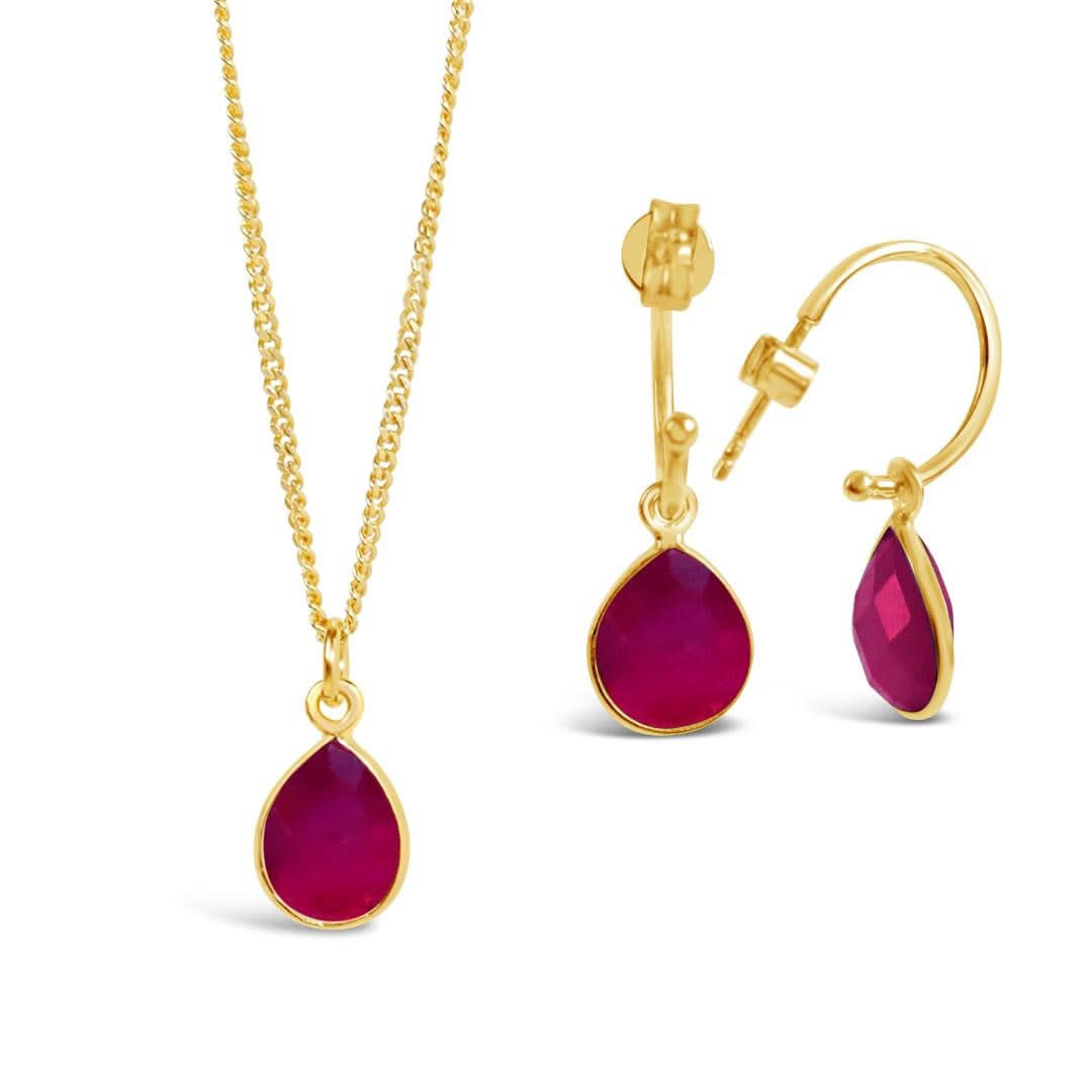 ruby drop hoop earrings and matching necklace in gold on a white background