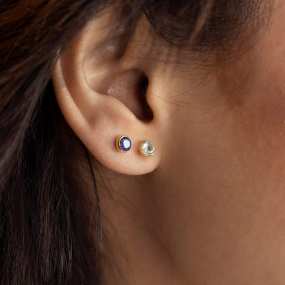 close up of model wearing blue topaz mini stud earrings in silver