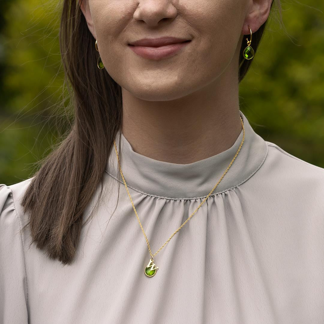 model wearing peridot charm necklace in gold with matching hoop earrings