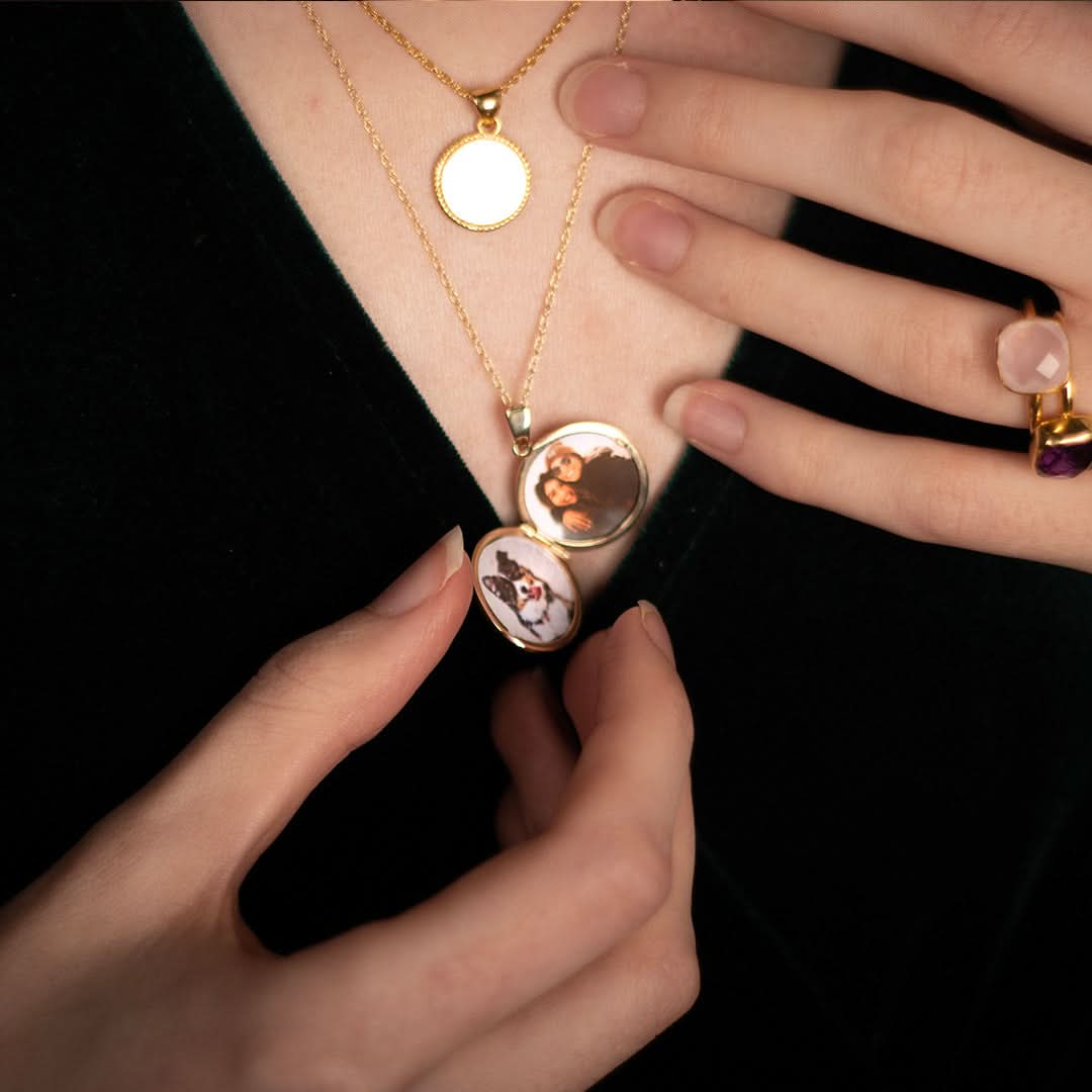 close up of model wearing gold round diamond locket with family photos insides